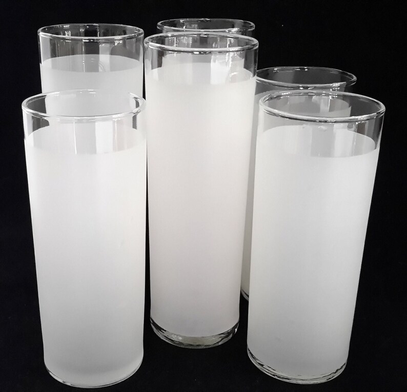May include: Six frosted glass tumblers, all white, with a slightly rounded shape. The glasses are arranged in a row, with the front three slightly overlapping the back three.