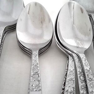 May include: A collection of shiny, silver spoons and serving utensils. The handles are decorated with a floral pattern. The spoons have a classic, elegant design, perfect for formal dining or special occasions.