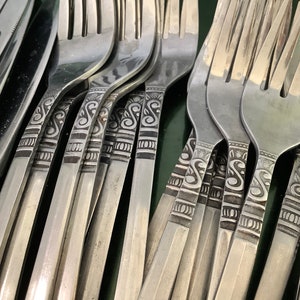 Peut inclure: Gros plan sur un ensemble de fourchettes en argent avec un motif orné. Les fourchettes sont disposées en rangée, les dents vers le haut.