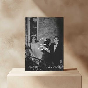 May include: A black and white save the date card featuring a photograph of a couple in front of a brick building. The text reads "Save the Date", "Ella and Ace", "San Francisco, California", "9 Jul 2024", and "Invite to Follow".