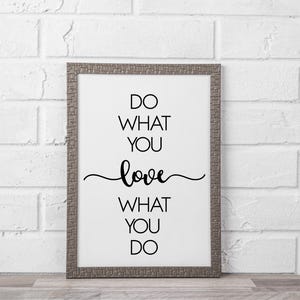 May include: A framed print with the text "DO WHAT YOU LOVE, LOVE WHAT YOU DO" in black script. The frame is a textured gray color, and the background is white. The print is displayed against a white brick wall.