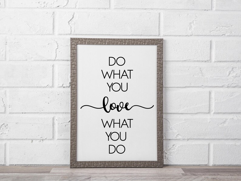 May include: A framed print with the text "DO WHAT YOU LOVE, LOVE WHAT YOU DO" in black script. The frame is a textured gray color, and the background is white. The print is displayed against a white brick wall.