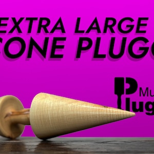 May include: A large wooden cone plug with a rounded base. The plug is light brown with a natural wood grain pattern. The text "EXTRA LARGE CONE PLUGG" is displayed in black letters on a bright pink background. The text "Mugglugg" is also displayed in black letters on a pink background.