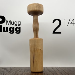May include: A wooden mallet with a round head and a cylindrical handle. The mallet is 2 1/4 inches tall. The mallet is made of light brown wood with a natural grain pattern.