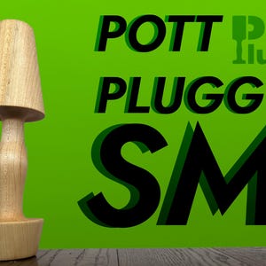 May include: A wooden pot plug with the text "Pott Plugg SM" in black letters on a green background. The text is in a 3D style with a shadow effect.