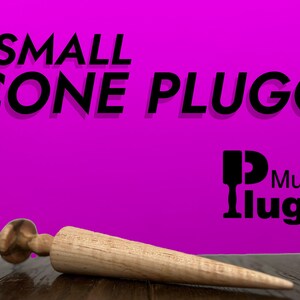 May include: A small wooden cone-shaped plug, also known as a "cone plug", is lying on a wooden surface. The plug is made of light brown wood and has a rounded tip. The text "SMALL CONE PLUGG" is displayed in black letters on a bright pink background. The text "Mugglugg" is also displayed in black letters on the pink background.