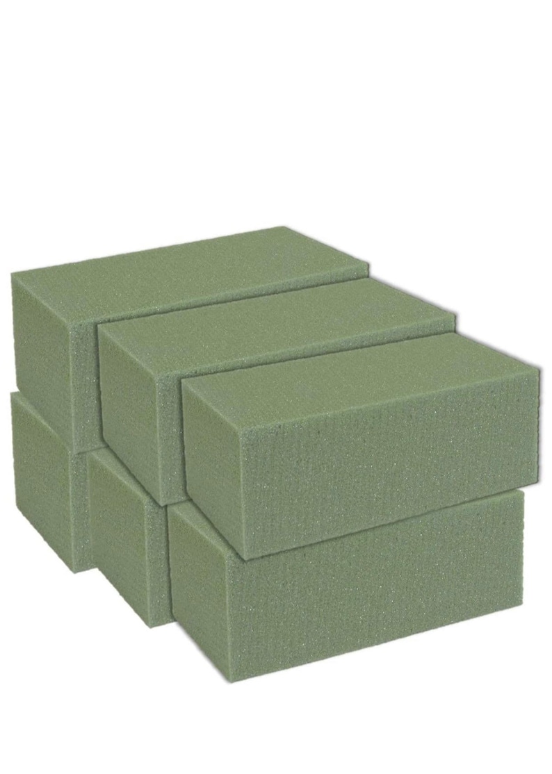 May include: A stack of six green floral foam bricks. The bricks are rectangular and have a slightly textured surface.