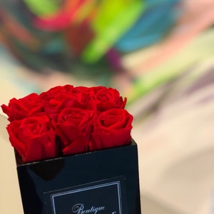 May include: A black square box with a red rose arrangement. The box has a white label with the text "Boutique Rouge".