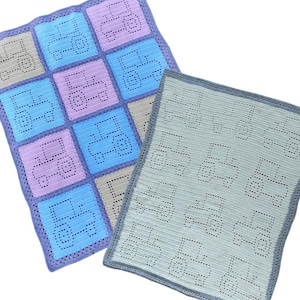 May include: Two crocheted baby blankets featuring a truck design. One blanket is blue, pink, and grey with a truck design in each square. The other blanket is light blue with a truck design repeated throughout.