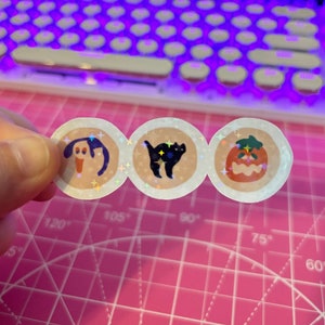 Pu&ograve; includere: Tre adesivi olografici rotondi a tema Halloween. Gli adesivi raffigurano un gatto nero, una zucca e un fantasma.