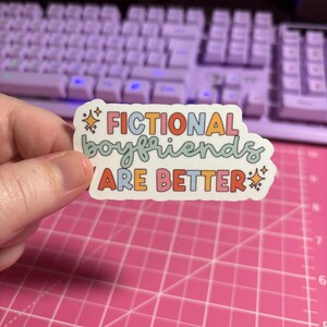 May include: A sticker with the text "Fictional boyfriends are better" in rainbow colors with stars on either side.