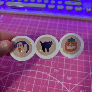 Pu&ograve; includere: Tre adesivi rotondi con finitura glitterata. Gli adesivi raffigurano un cane dei cartoni animati, un gatto nero e una zucca di Halloween.