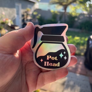 May include: A holographic sticker of a coffee pot with the text "Pot Head" in black lettering.