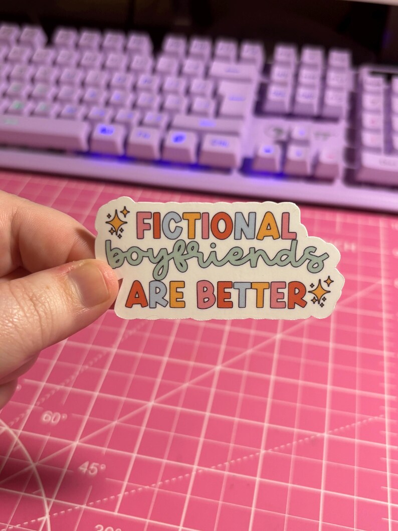 May include: A sticker with the text "Fictional boyfriends are better" in rainbow colors with glitter accents.