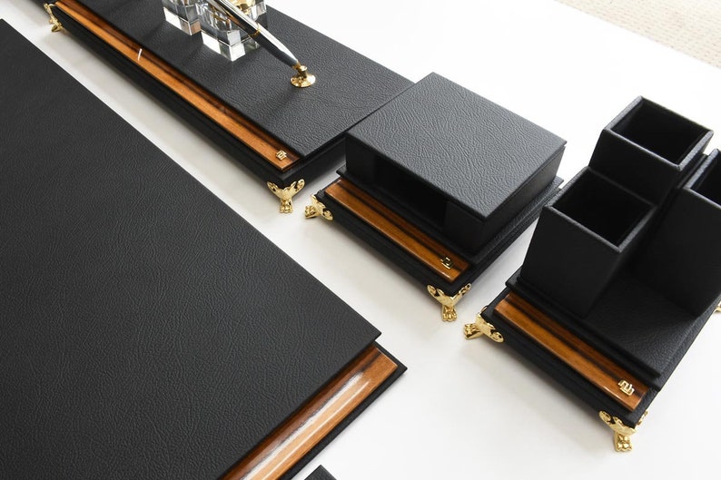 May include: Black leather desk organizer set with gold accents. The set includes a pen holder, a letter holder, and a multi-compartment organizer.