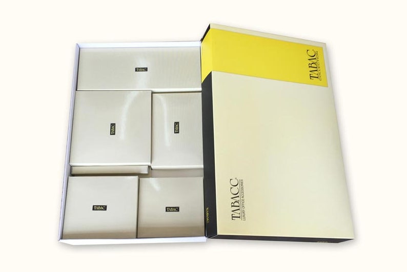May include: A white box with six smaller boxes inside. The smaller boxes are all white with the word "TABACC" printed on them. The larger box is yellow and white with the text "TABACC" printed on it.