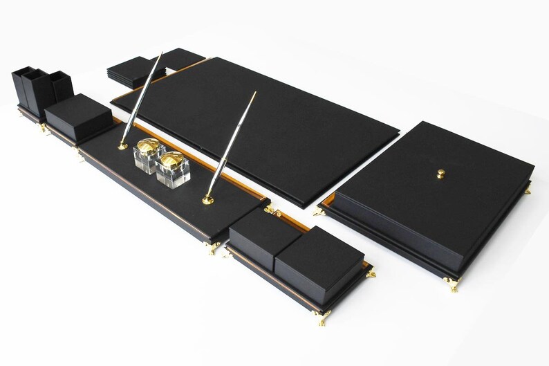 May include: Black leather desk organizer set with gold accents. The set includes a writing pad, pen holders, and a tray for office supplies.