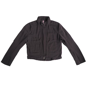 Puede incluir: Chaqueta marrón oscuro con cuello alzado y cremallera completa. La chaqueta tiene mangas largas y dos bolsillos delanteros. La chaqueta está hecha de un material liso, posiblemente sintético.