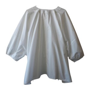 May include: A white, loose-fitting top with three-quarter sleeves. The garment has a rounded neckline and a flowing, oversized silhouette. The fabric appears to be a lightweight material, suitable for warmer weather. The sleeves are gathered at the elbow.