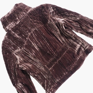 May include: A mauve velvet jacket with a high collar and long sleeves. The jacket has a quilted design and a zipper closure.
