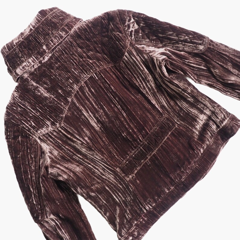 May include: A mauve velvet jacket with a high collar and long sleeves. The jacket has a quilted design and a zipper closure.