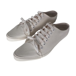 Puede incluir: Un par de zapatillas de lona color crema con cordones blancos. Las zapatillas tienen un diseño de perfil bajo con suela de goma y puntera redondeada. Los zapatos son nuevos y limpios, ideales para uso casual.