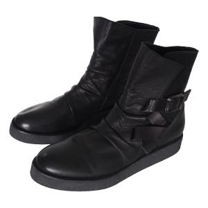 May include: A pair of black ankle boots featuring a smooth leather upper with subtle ruching, a rounded toe, and a side strap with a dark metal buckle. The boots are set on a thick, textured dark gray rubber sole with a flat profile and low heel.