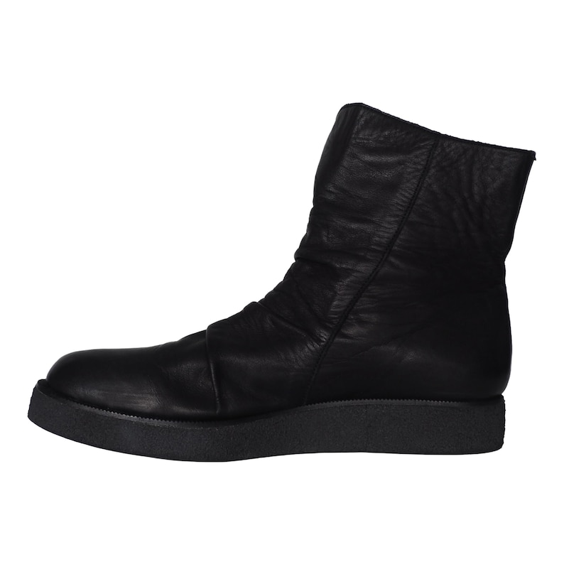 May include: A black leather ankle boot with a smooth, matte finish and a slightly ruched upper. The boot features a rounded toe, a high shaft, and a thick, textured black rubber platform sole that provides a flat, stable base for the footwear.