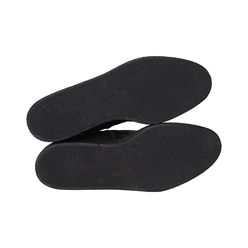 May include: A pair of black shoes shown from the bottom view, featuring flat, solid black rubber outsoles with a smooth, uniform texture. The soles are oval-shaped and lack any visible tread patterns, logos, or markings on the surface.