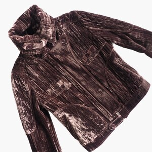 May include: A brown velvet jacket with a high collar and multiple pockets. The jacket has a zipper closure and a quilted design.