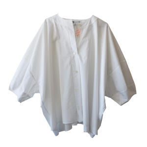 May include: A white, oversized button-down shirt with a mandarin collar and three-quarter sleeves. The shirt has a relaxed fit and a simple, minimalist design. The fabric appears to be a lightweight cotton or linen blend.