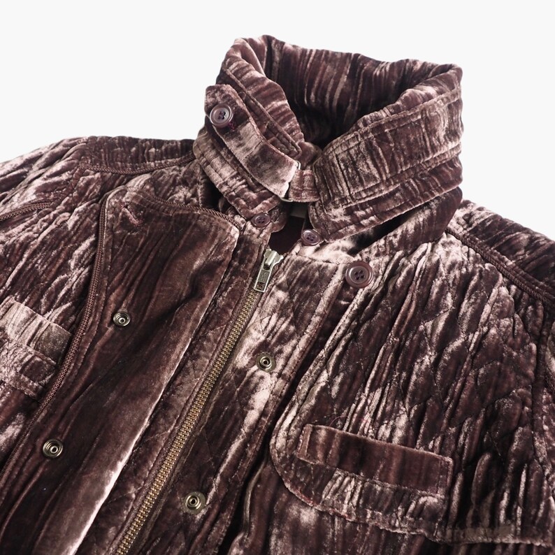 May include: A brown velvet jacket with a zipper closure and multiple pockets. The jacket has a quilted design and a high collar.