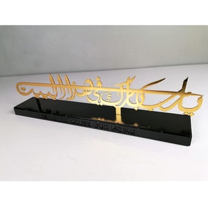 May include: Gold metal wall decor with Arabic calligraphy that reads "Ya Allah Bless Our Home" on a black base.
