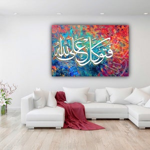 May include: A white couch with red throw blanket in front of a colorful abstract painting with Arabic calligraphy that reads "Allah" and "Muhammad".