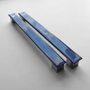 May include: Two blue glass cabinet door pulls with a textured finish and silver metal bases.