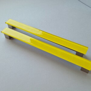 May include: Two yellow glass cabinet door pulls with a brushed nickel finish.