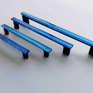 Fired glass cabinet pulls in sparkly bright blue made of fine glass sticks attached over a metal base. Slightly textured glass furniture handles with rounded edges.