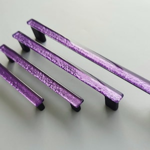 Fired glass cabinet pulls in sparkly purple made of fine glass sticks attached over a metal base. Slightly textured glass furniture handles with rounded edges.