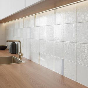 以下が含まれることがあります： 木製のカウンタートップ、ステンレス製のシンク、金色の蛇口を備えたモダンなキッチンデザイン。白い正方形のタイルがバック splash を形成し、その上に照明付きの木製棚があります。濃い緑色のキャビネットが見えます。