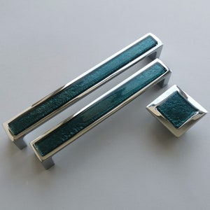 May include: Two teal blue glass cabinet pulls with chrome accents and a matching teal blue glass knob with chrome accents.