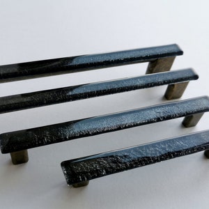 Fired glass cabinet pulls in sparkly bright black made of fine glass sticks attached over a metal base. Slightly textured glass furniture handles with rounded edges.