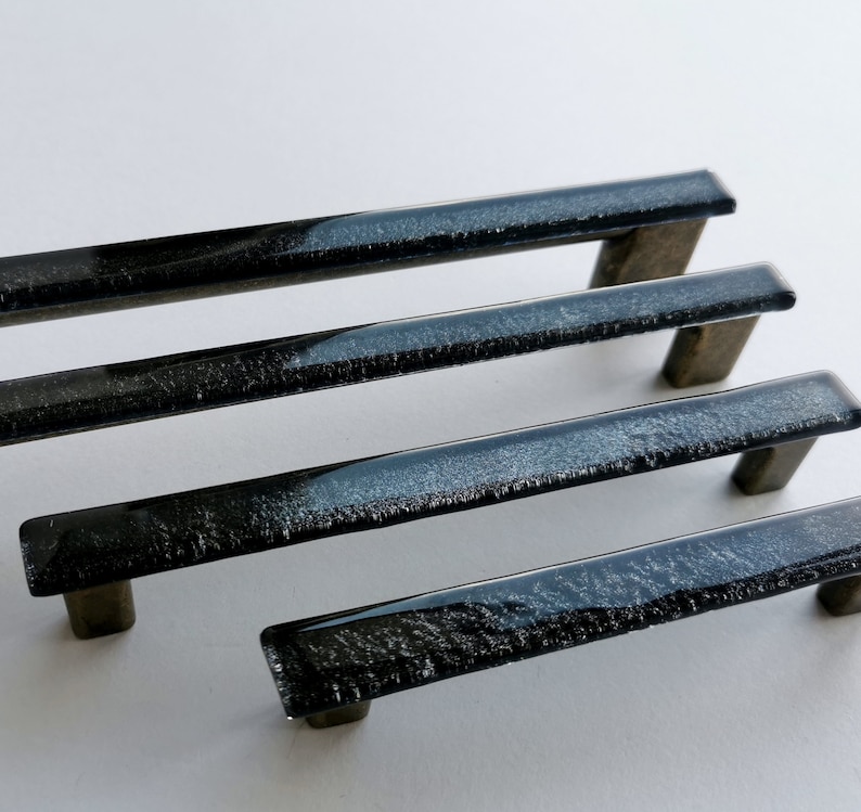 Fired glass cabinet pulls in sparkly bright black made of fine glass sticks attached over a metal base. Slightly textured glass furniture handles with rounded edges.