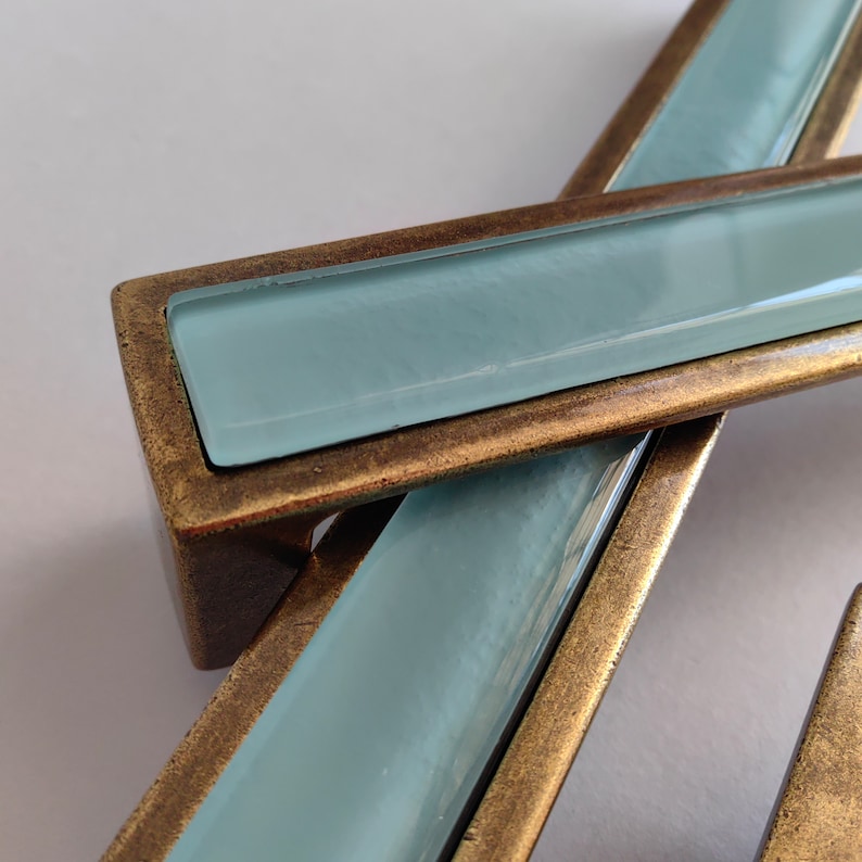 May include: Two cabinet pulls with a light blue glass insert and a brass frame.