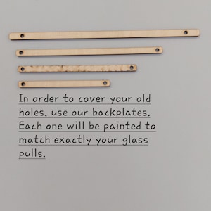Puede incluir: Cuatro placas traseras de madera de diferentes longitudes con agujeros perforados en cada extremo. Las placas traseras están diseñadas para cubrir los agujeros viejos en los armarios o cajones. El texto dice: "Para cubrir tus viejos agujeros, usa nuestras placas traseras. Cada una será pintada para que coincida exactamente con tus tiradores de vidrio."