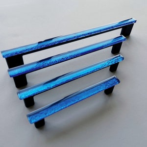 Fired glass cabinet pulls in sparkly bright blue made of fine glass sticks attached over a metal base. Slightly textured glass furniture handles with rounded edges.