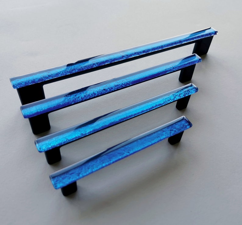 Fired glass cabinet pulls in sparkly bright blue made of fine glass sticks attached over a metal base. Slightly textured glass furniture handles with rounded edges.