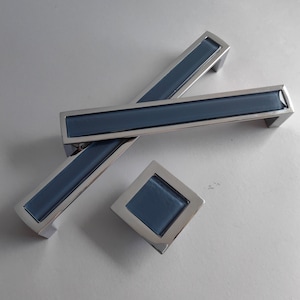 May include: Three cabinet hardware pulls in a chrome finish with a blue glass insert. Two are rectangular and one is square.
