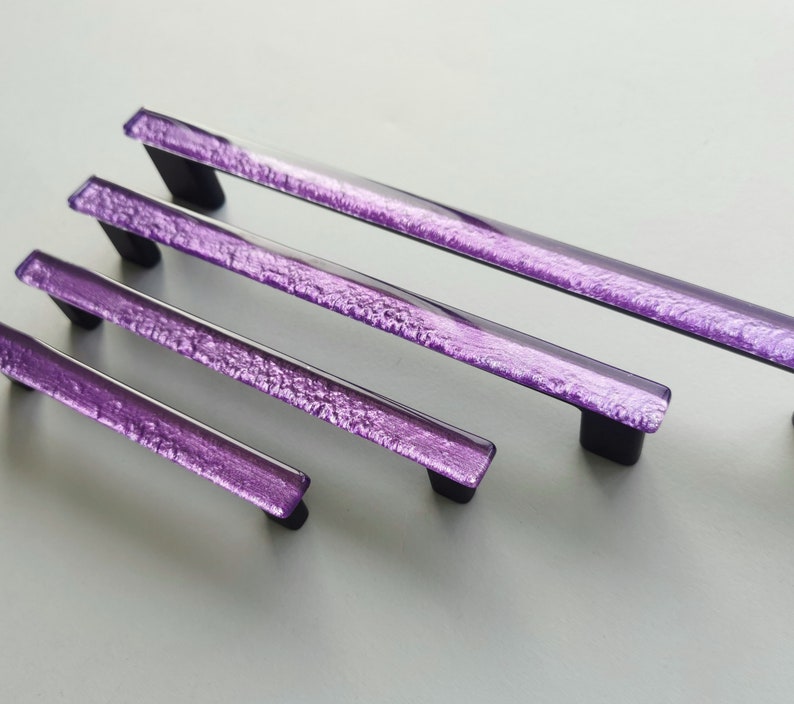 Fired glass cabinet pulls in sparkly purple made of fine glass sticks attached over a metal base. Slightly textured glass furniture handles with rounded edges.