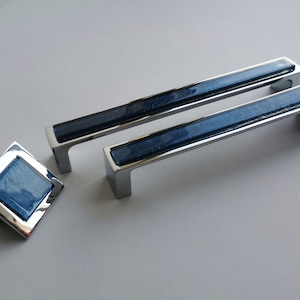 Peut inclure: Deux poignées de tiroir en chrome avec des inserts en verre bleu et un bouton carré assorti.