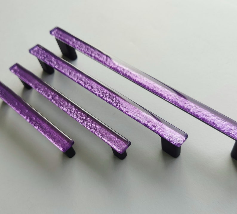 Fired glass cabinet pulls in sparkly purple made of fine glass sticks attached over a metal base. Slightly textured glass furniture handles with rounded edges.